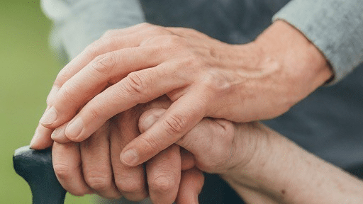 Hands offering comfort and support to elderly person.